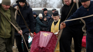 Pale with grief, a Ukrainian girl buries her family