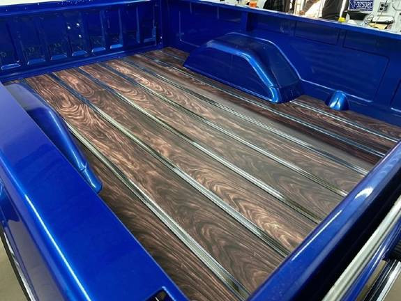 Angled view of the aluminum bed floor with wood-grain finish in a blue bed